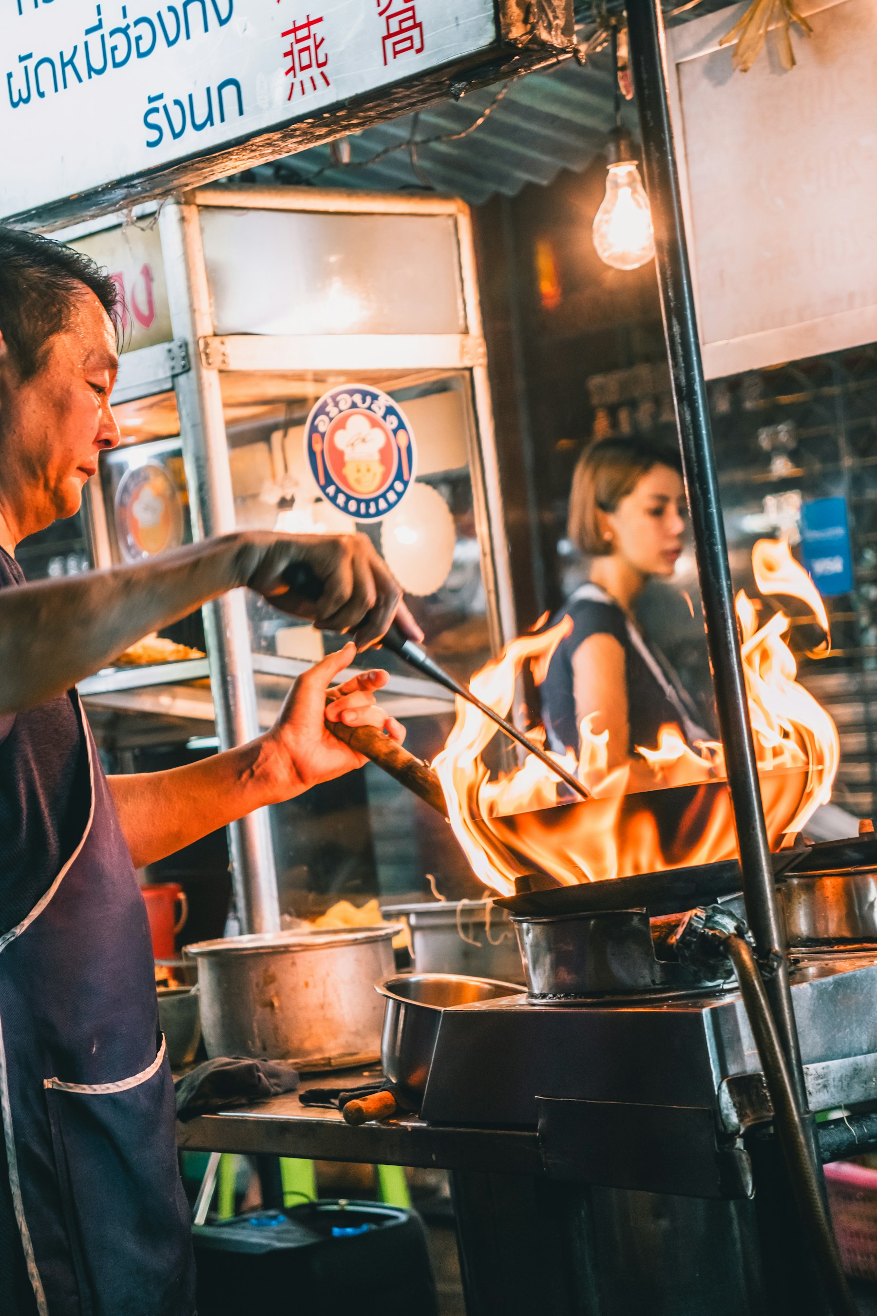 Koch bereitet ein Gericht über der offenen Wok-Flamme zu